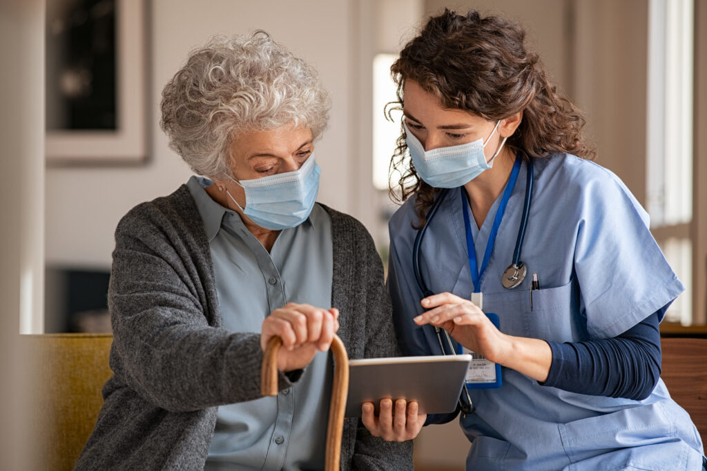 Nurse assisting elderly woman using tablet